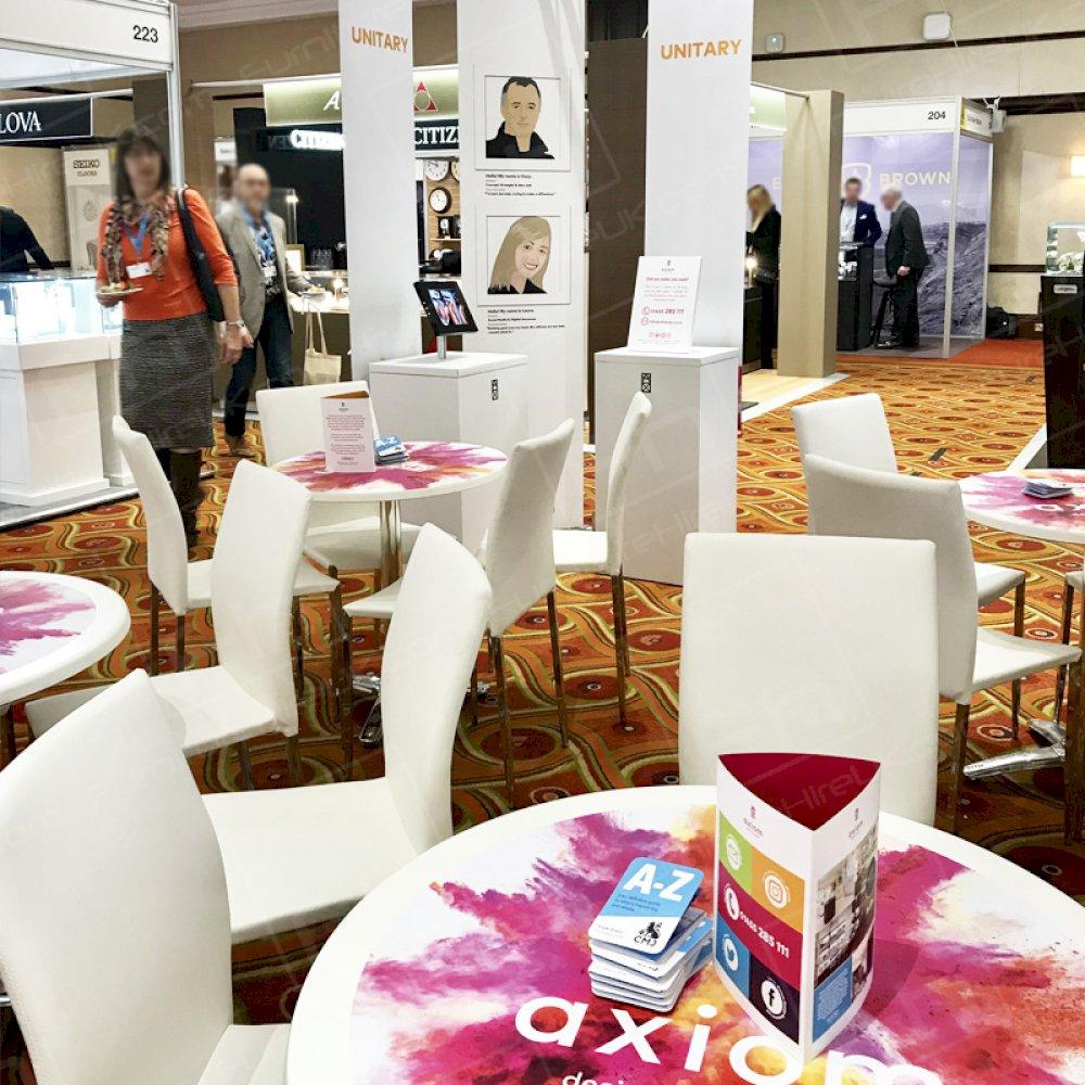 White tables and chairs hired for an exhibition seating area.